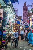 Rabat, Morocco, Apr 24 2015, Local shoppers and visitors stroll through the vibrant shops of Rabat\'s old town, with a historic tower towering in the background as dusk approaches.