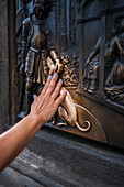 Tourists touching a plaque that is part of the statue St. John of Nepomuk for good luck, Prague.