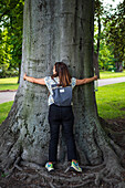 Woman hugging a tree in a park of Prague