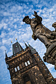 Statue des Heiligen Ivo von Kermartin und alter Turm an der Karlsbrücke in Prag