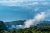 A plume of mist rises from the Devil's Throat or Garganta del Diablo at sunrise at Iguazu Falls National Park in Argentina. A UNESCO World Heritage Site. Brazil is on the left side of the canyon, with Argentina on the right.