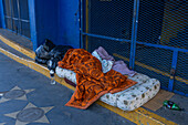 A homeless person asleep on a mattress on the step of La Bombonera Stadium in La Boca, Buenos Aires, Argentina.