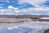 Salt mining operations on the salt flats of Salinas Grandes in northwest Argentina. Clouds are reflected on a shallow sheet of water.