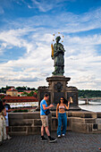 Tourists touching a plaque that is part of the statue St. John of Nepomuk for good luck, Prague.