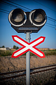 Close up image of a railroad crossing sign, symbolizing caution and safety at a sunny railway intersection.