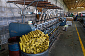 Leere Garnspulen, die in der Weberei Hilandería Warmi in Palpalá, Argentinien, zum Aufspulen von Garn wiederverwendet werden. Diese Maschine wickelt das Garn von den kleineren Spulen auf größere Spulen