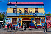 Tourists and caricature statues of people in front of a shop in Caminito, La Boca, Buenos Aires, Argentina. Among those portrayed are Eva Peron, Diego Maradona and a musician playing a bandoneon.