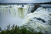 The water of the Iguazu River falls over the precipice of the Garganta del Diablo or the Devil's Throat Waterfall in Iguazu Falls National Park in both Argentina and Brazil. Both parks are UNESCO World Heritage Sites. At left is Brazil, at right is Argentina.