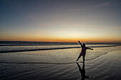 Sunset on the beach in Las Lajas, Panama. Person stands on the beach silhouetted.