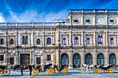 Carriages wait in front of the ornate Plateresque facade of Seville City Hall, showcasing historic architecture in vibrant Andalucía.