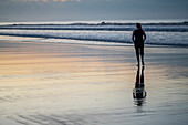 Sunset on the beach in Las Lajas, Panama. Person walks on the beach silhouetted.