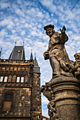 Statue des Heiligen Ivo von Kermartin und alter Turm an der Karlsbrücke in Prag