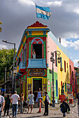 A tourist poses for a photo on Caminito Street in La Boca, Buenos Aires, Argentina.