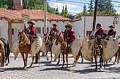 Gauchos in traditional outfits ride in on horseback for a parade in Cachi, Argentina. Cowhide guardemontes protect the riders from thorn bushes common in the area.