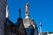 Crosses & a statue on elaborate tombs or mausoleums in the Recoleta Cemetery, Buenos Aires, Argentina.