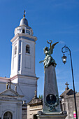 Eine Engelsstatue auf einem Mausoleum auf dem Friedhof von Recoleta in Buenos Aires, Argentinien. Dahinter befindet sich der Glockenturm der Basilika Nuestra Senora del Pilar