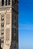 The iconic Giralda tower stands majestically against a clear blue sky, showcasing intricate designs and rich history in Seville, Spain.