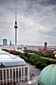 The iconic Fernsehturm stands tall against the skyline, captured from the dome of a historic cathedral in Berlin.