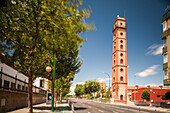 The Torre de los Perdigones illuminated against the skyline, captured in a long exposure showing motion amidst a quiet street.