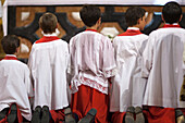 Altar boys kneel in prayer at the conclusion of the Corpus Christi procession in Sagrario church, Seville, captured in 2009.