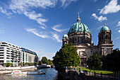 The Berliner Dom overlooks the Spree River, showcasing its stunning architecture against a clear blue sky in Berlin.