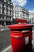 A classic red post box stands prominently on Regent Street, surrounded by busy streets and shops in Westminster, London.