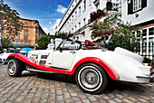 A classic vintage car stands elegantly on the cobbled streets of Kensington, showcasing timeless design and local charm.