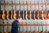 Seville, Spain Jan 13 2007, A variety of guitars are showcased on the wall of a music store in Seville, while a man walks by in the foreground.