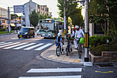 Kids on bikes waiting to cross a street of Kyoto, Japan