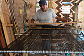 A man weaving on a wooden foot loom in Seclantas, Argentina in the Calchaqui Valley.