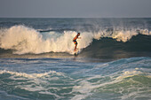 Mann beim Surfen am Strand vor der Finca Barlovento, Tayrona National Park, Kolumbien