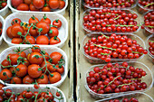 Vibrant cherry tomatoes and currants are displayed fresh at the lively Mercado de la Boquería, showcasing local produce.