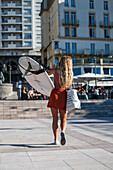 Young woman carrying her surf board on Grande Plage beach of Biarritz, France