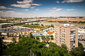 Enjoy a panoramic view of Seville along the Guadalquivir River, showcasing lush greenery and urban development under a clear sky.