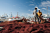 Seville, Spain, Aug 7 2008, Fishermen work together to mend nets under a clear sky at Bonanza port in Sanlucar de Barrameda, Cadiz, Andalusia.