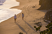 Couple walking on the beach in front of Finca Barlovento at sunset, Tayrona National Park, Colombia