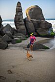 Kid walking his dog on the beach in front of Finca Barlovento, Tayrona National Park, Colombia