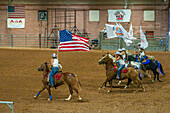 Cowgirls in a mounted drill team perform with flags at the beginning of the Moab Junior Rodeo in Moab, Utah.