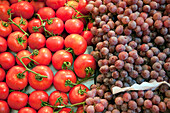 Colorful tomatoes and clusters of grapes displayed at Mercat de la Boqueria, showcasing the vibrant produce of Barcelonas market.