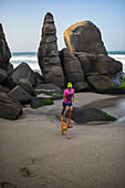 Kid walking his dog on the beach in front of Finca Barlovento, Tayrona National Park, Colombia