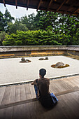 One man meditates at Japanese zen garden, Ryoan-Ji Temple in Kyoto