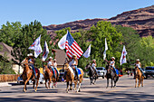 An equestrian drill team on horseback with an American flag in the Fourth of July Parade on Independence Day in Moab, Utah.