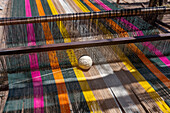 Colorful yarn on a wooden foot loom outside in a home weaving workshop in Seclantas, Argentina in the Calchaqui Valley.