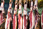 A variety of cured hams hang in a butchers stall at La Boqueria market, showcasing the vibrant food culture of Barcelona.