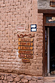 Carved wooden signs on the wall of a store in a traditional adobe brick building in Purmamarca, Argentina.