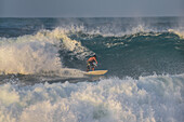 Mann surft am Strand vor der Finca Barlovento, Tayrona-Nationalpark, Kolumbien