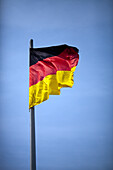 The German flag waves gracefully in the wind, symbolizing patriotism and national pride in Berlin, Germany, under a bright sky.