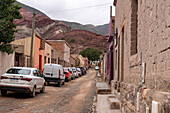 Straße Libertad in Purmamarca, Argentinien, mit dem Aussichtspunkt Cerro El Porito und dem Berg der sieben Farben dahinter und links