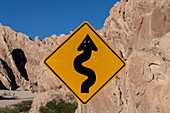 A humorously vandalized road sign along Route 40 in the Angastaco Natural Monument, Calchaqui Valley, Argentina.