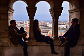 Tourists enjoy the view of Parliament building, Chain Bridge and Danube River through old columns, Budapest, Hungary, Europe